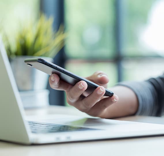 holding a phone near a laptop