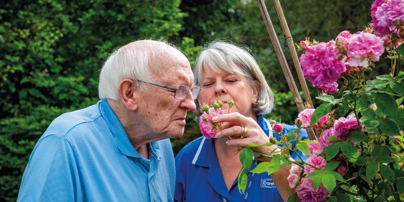 Man and care assistant smell flowers