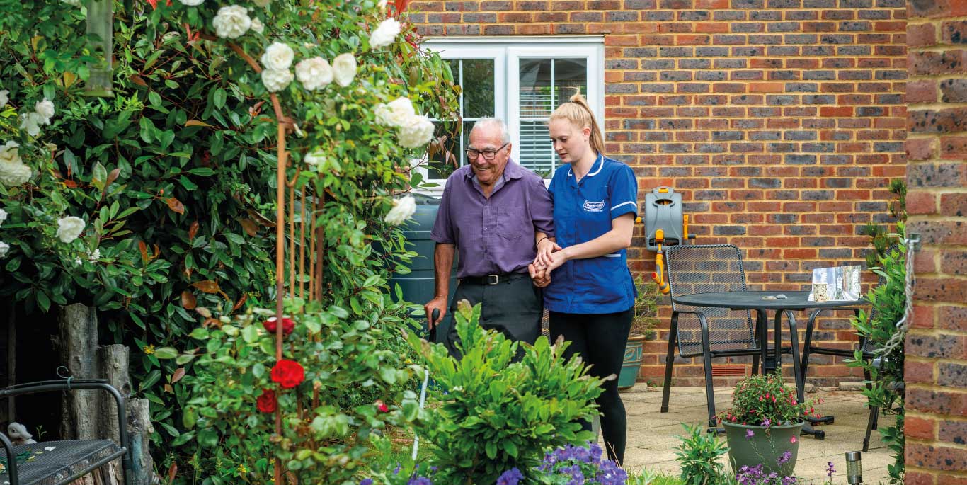 Domiciliary Care in Stratford Upon Avon : Female care assistant with male customer walking in the garden