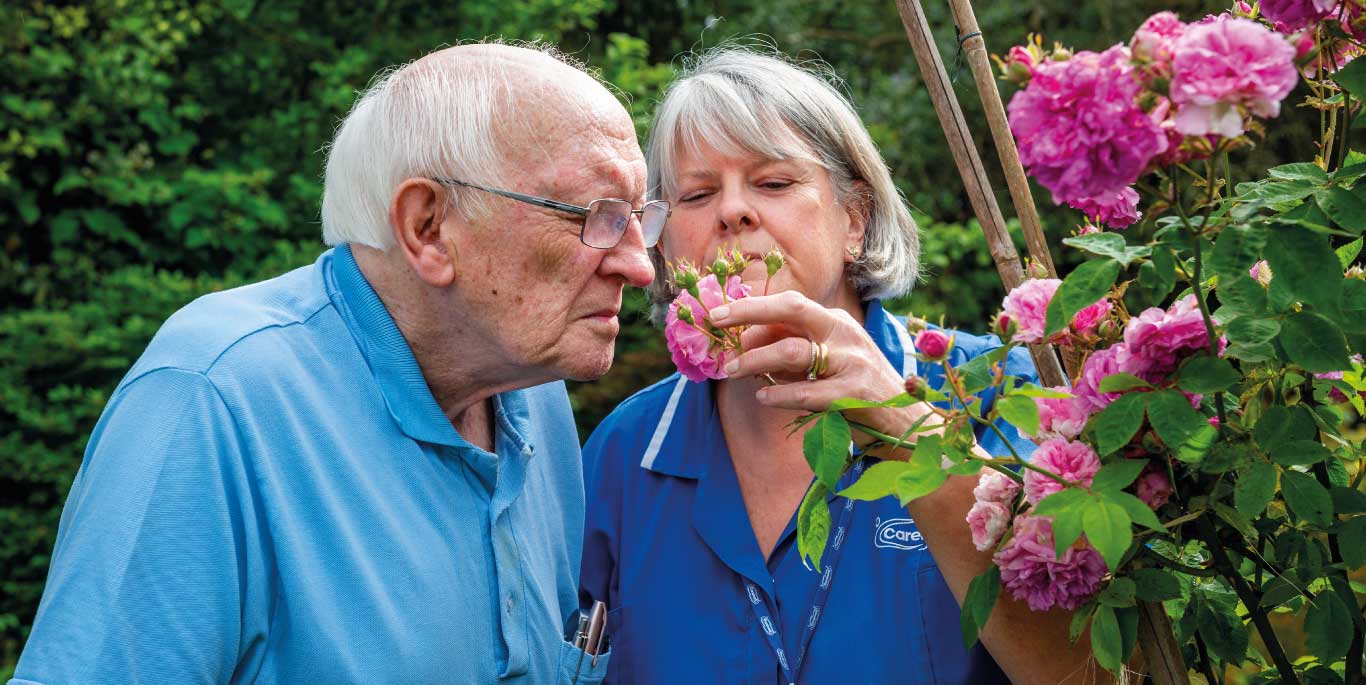 Man and care assistant smell flowers2