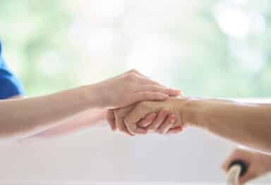 Care assistant holding clients hands