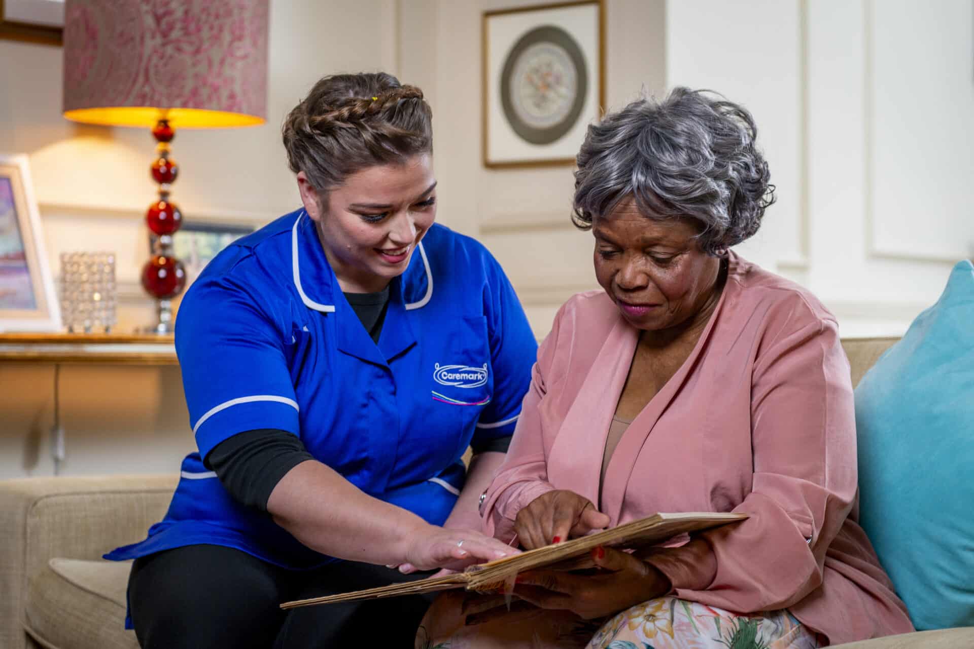 Companionship Care in Stratford Upon Avon: female care assistant looking through photo book with customer