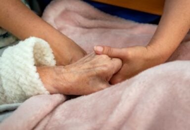 Close-up image of a compassionate care assistant holding hands with a customer, conveying warmth and support in a caring environment