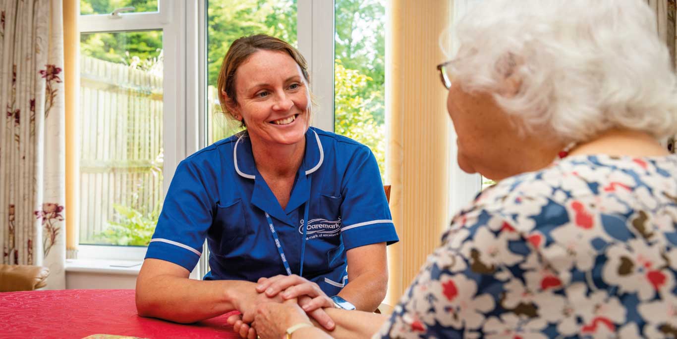 Woman and care assistant holding hands