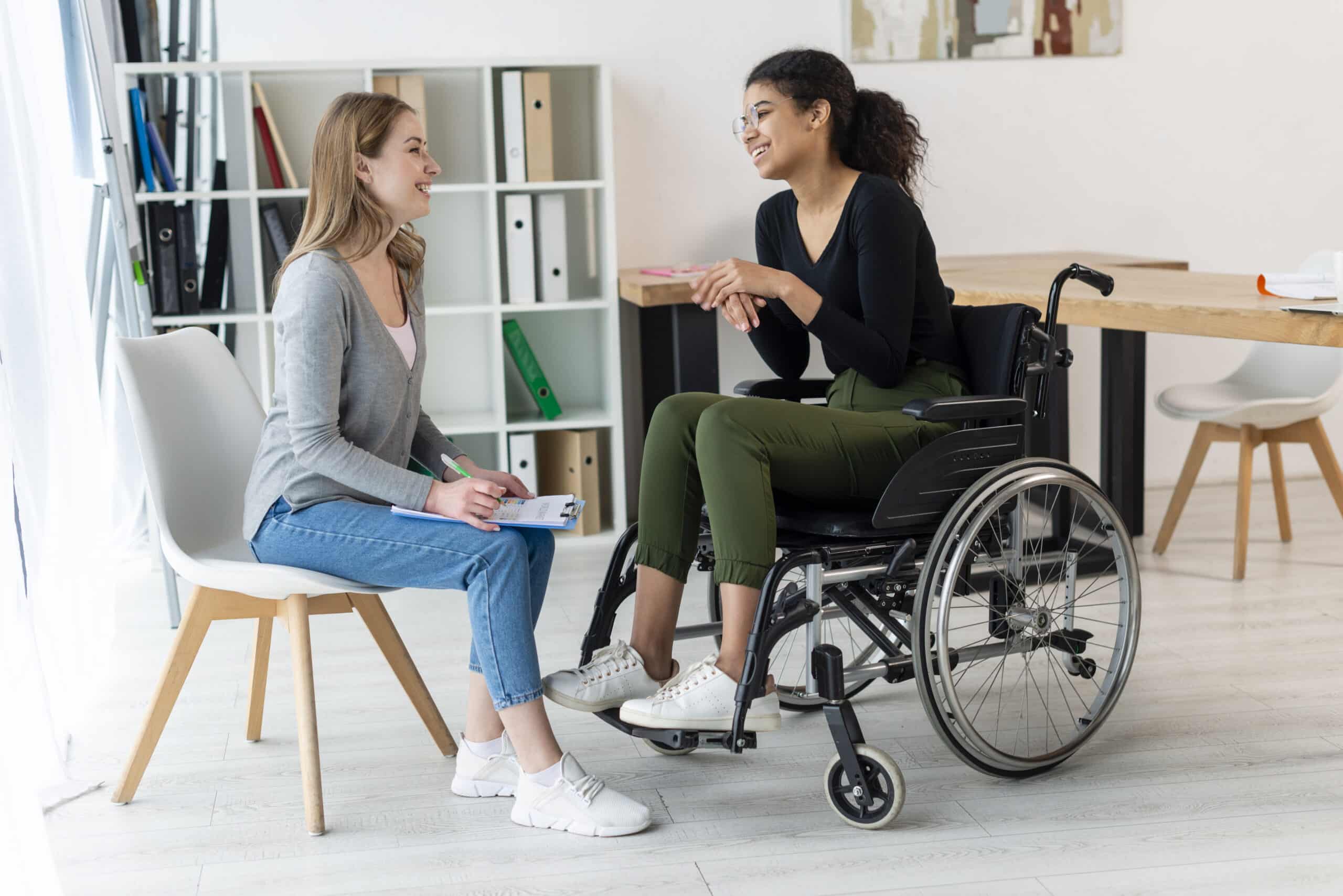 Disability care. Woman in wheelchair talking to a carer