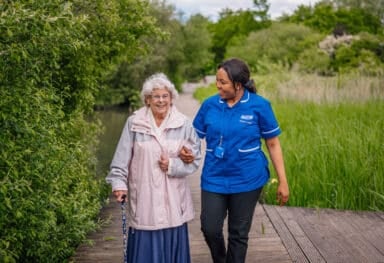 Person living with dementia enjoying a walk in Barking Park with a Caremark carer.