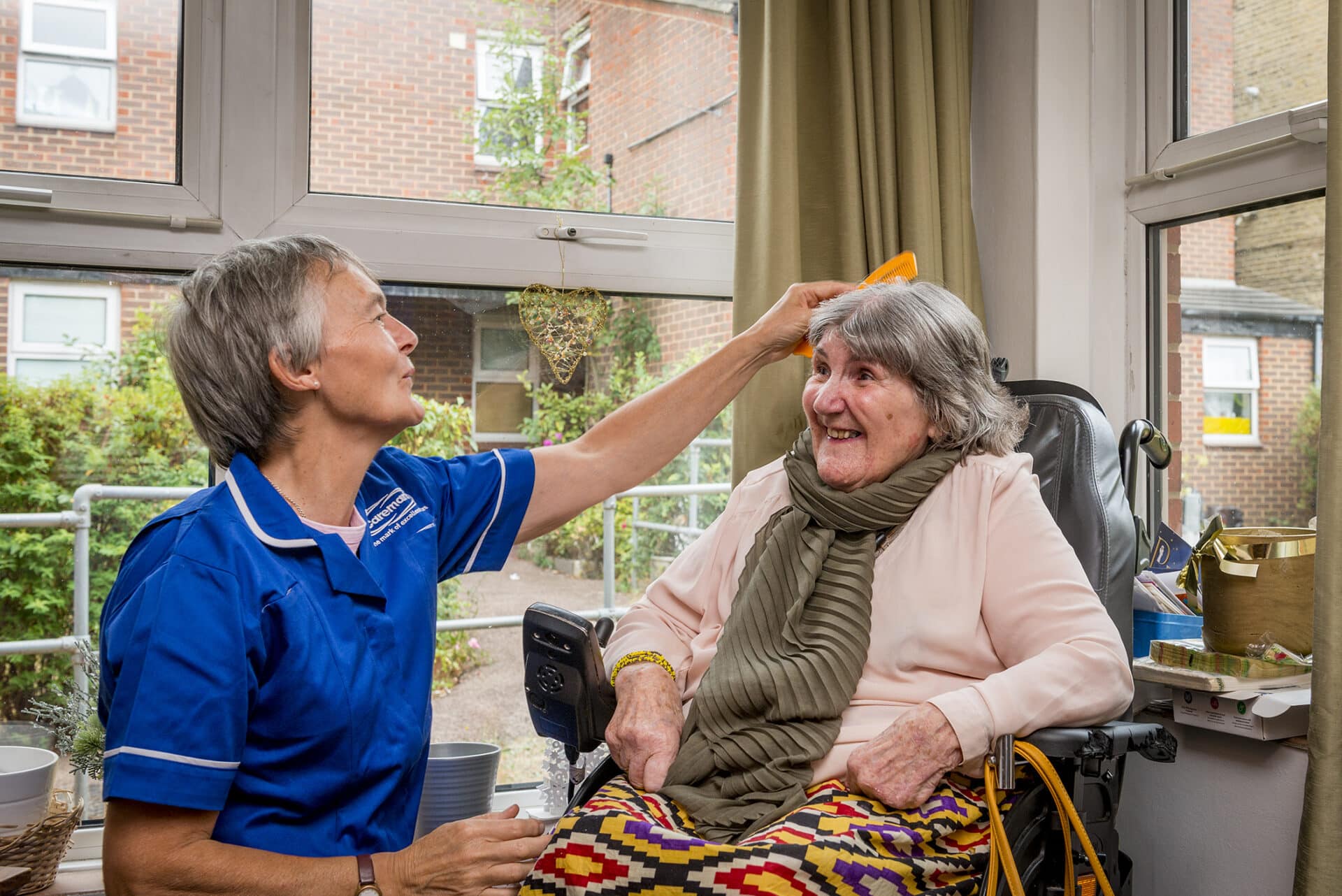 Care assistant brushing female service users hair