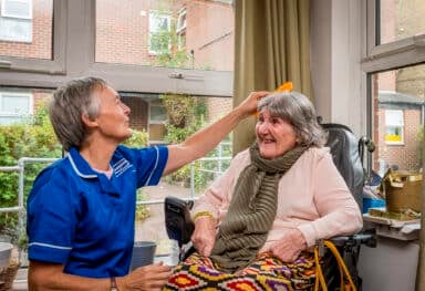 Care assistant brushing female service users hair