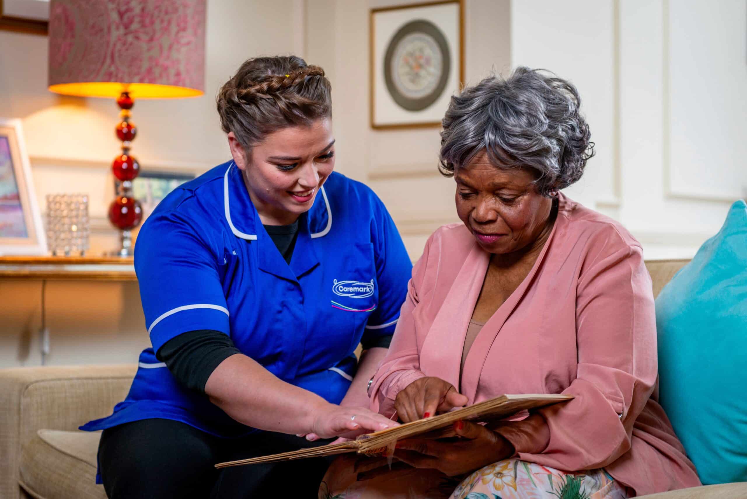 female care assistant smiling and going through memory book with female customer during respite care in North Lincolnshire
