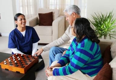 Home health care worker and an elderly couple playing game
