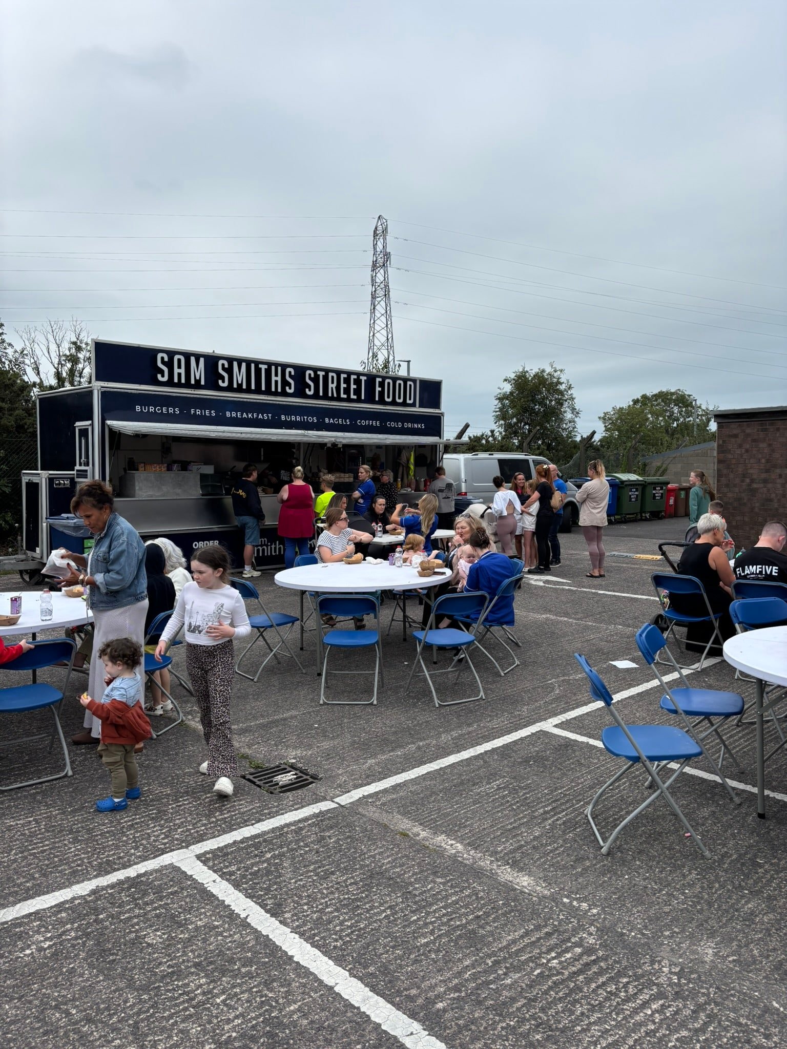 People enjoying food and chatting at outdoor tables from Sam Smith’s Street Food during the Caremark NI family fun day