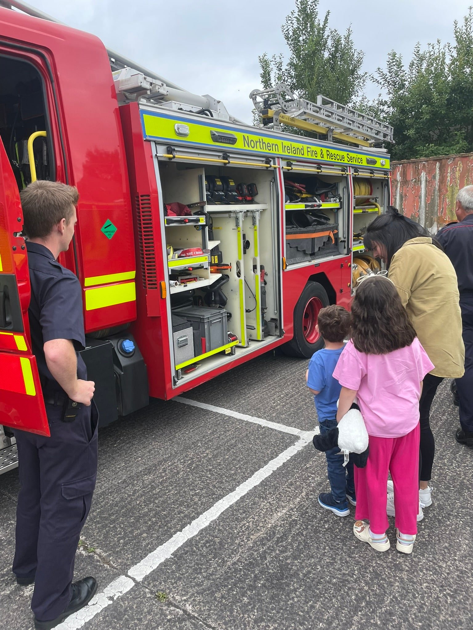 Children looking at the NIFRS fire engine while firefighters show them equipment at the Caremark NI family fun day