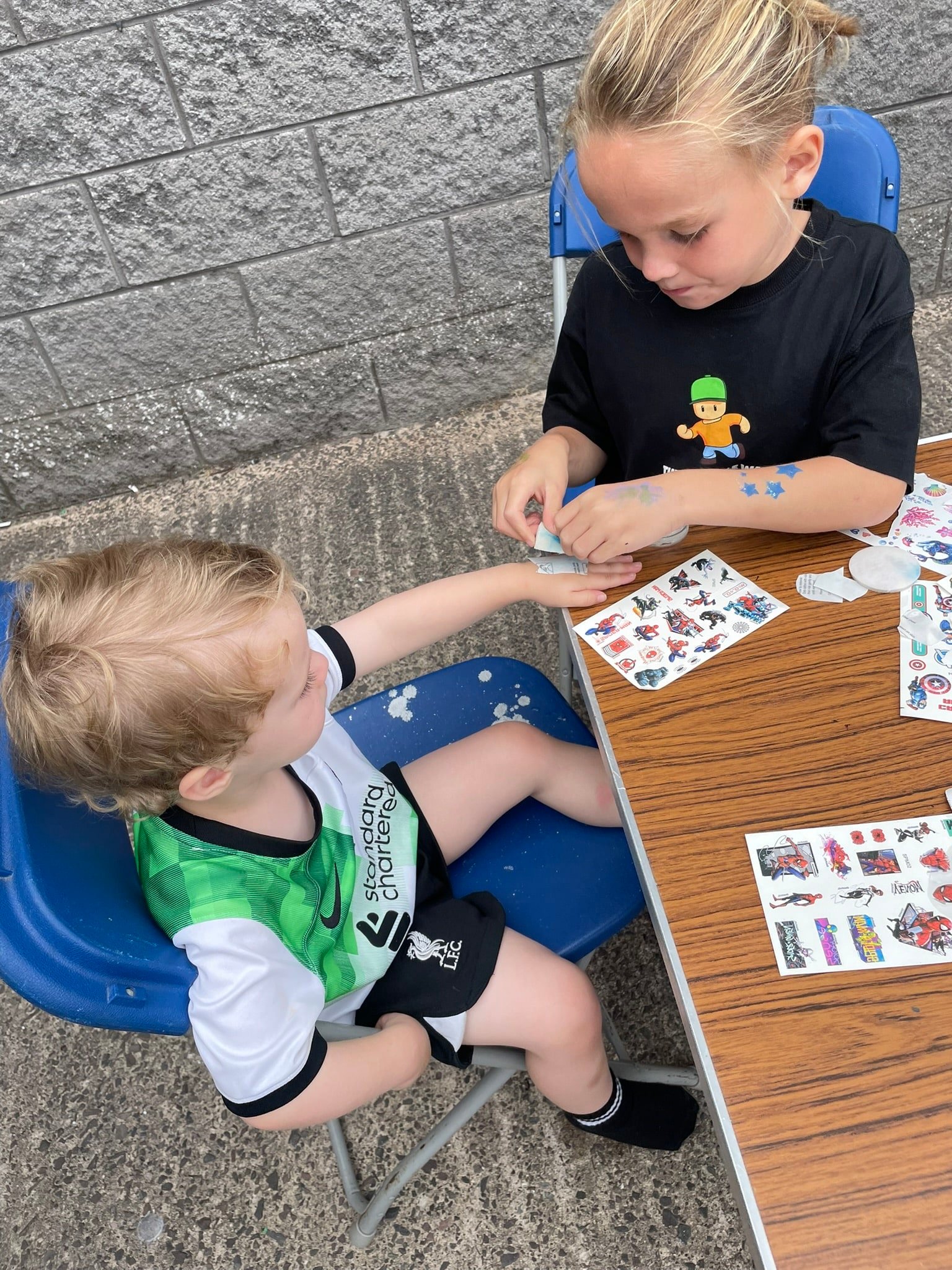 Two young boys putting stickers on each other and doing crafts at the Caremark NI family fun day