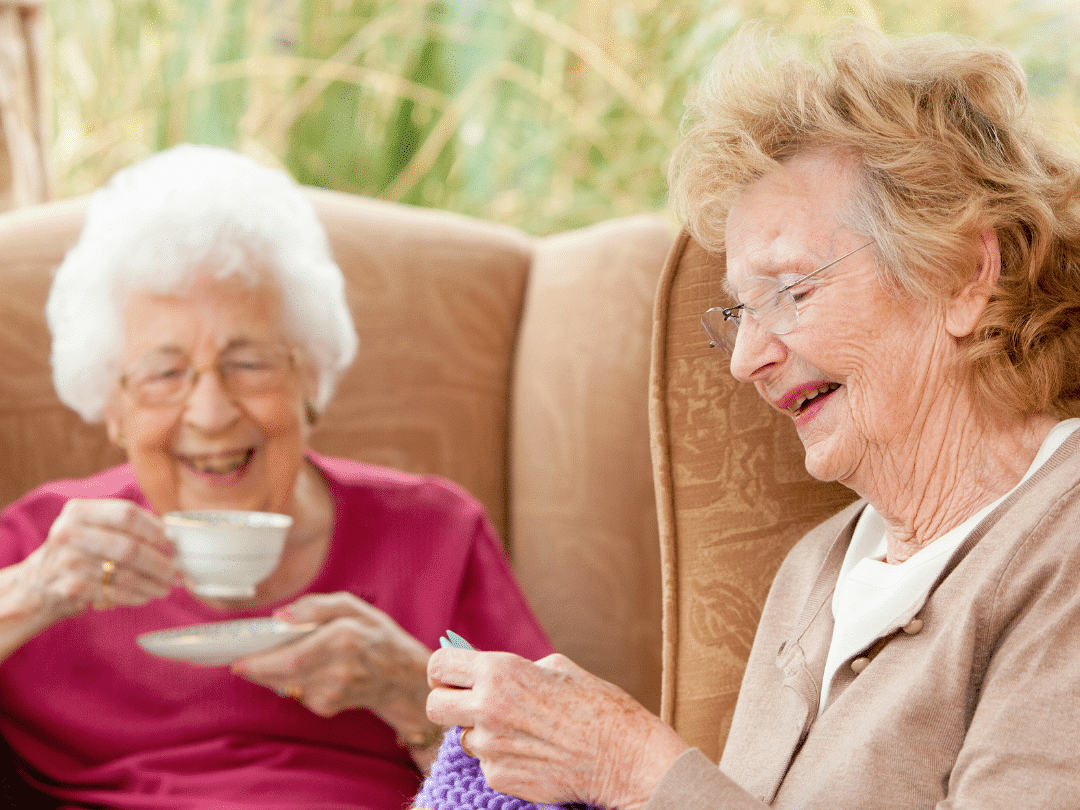older people socialising, one lady is drinking team and another lady is knitting for the winter