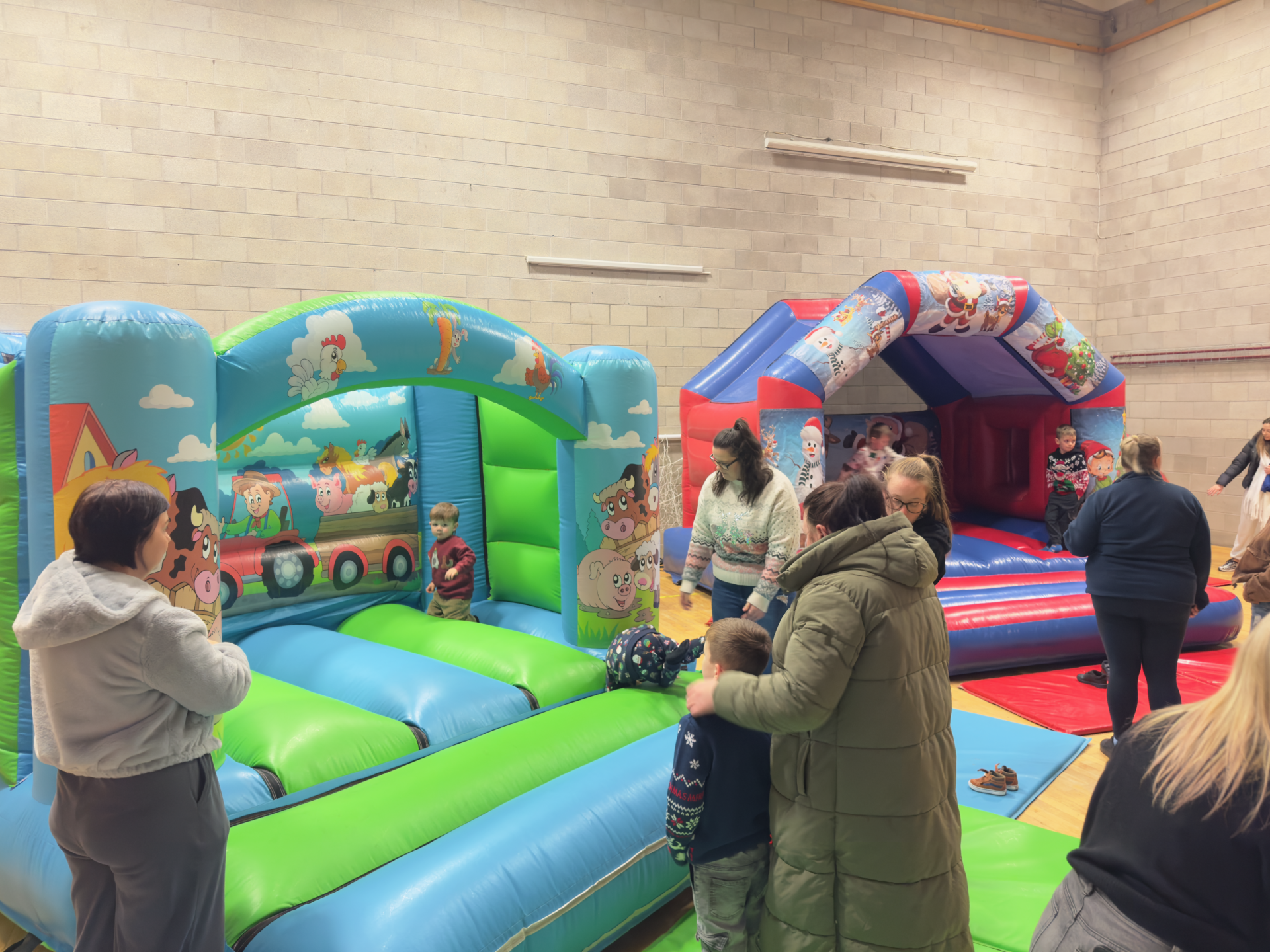 Two colourful bouncy castles set up inside with children playing on it