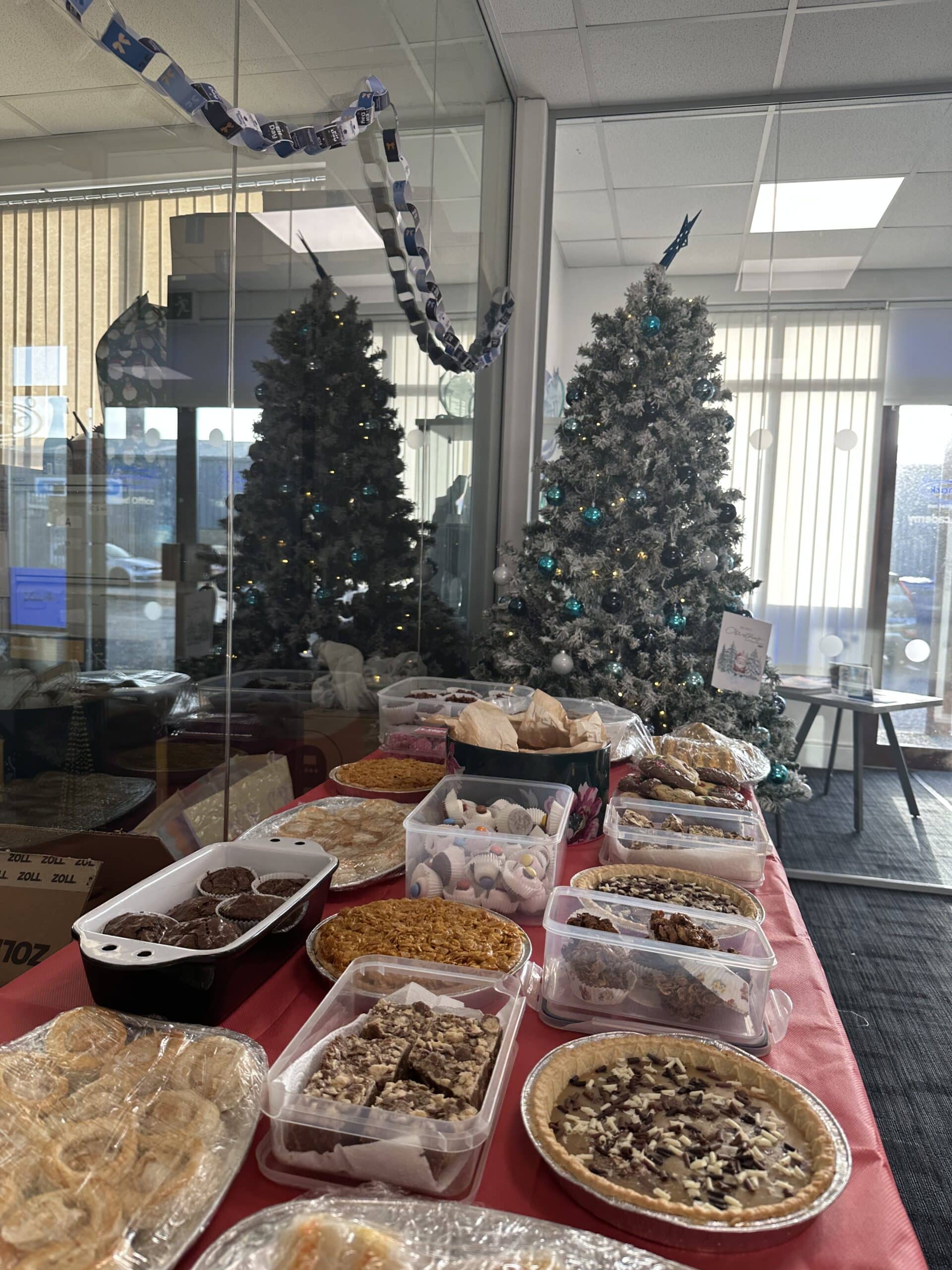 variety of homemade baked goods on a table in front of the christmas tree - Caremark NI Elf Day 2025