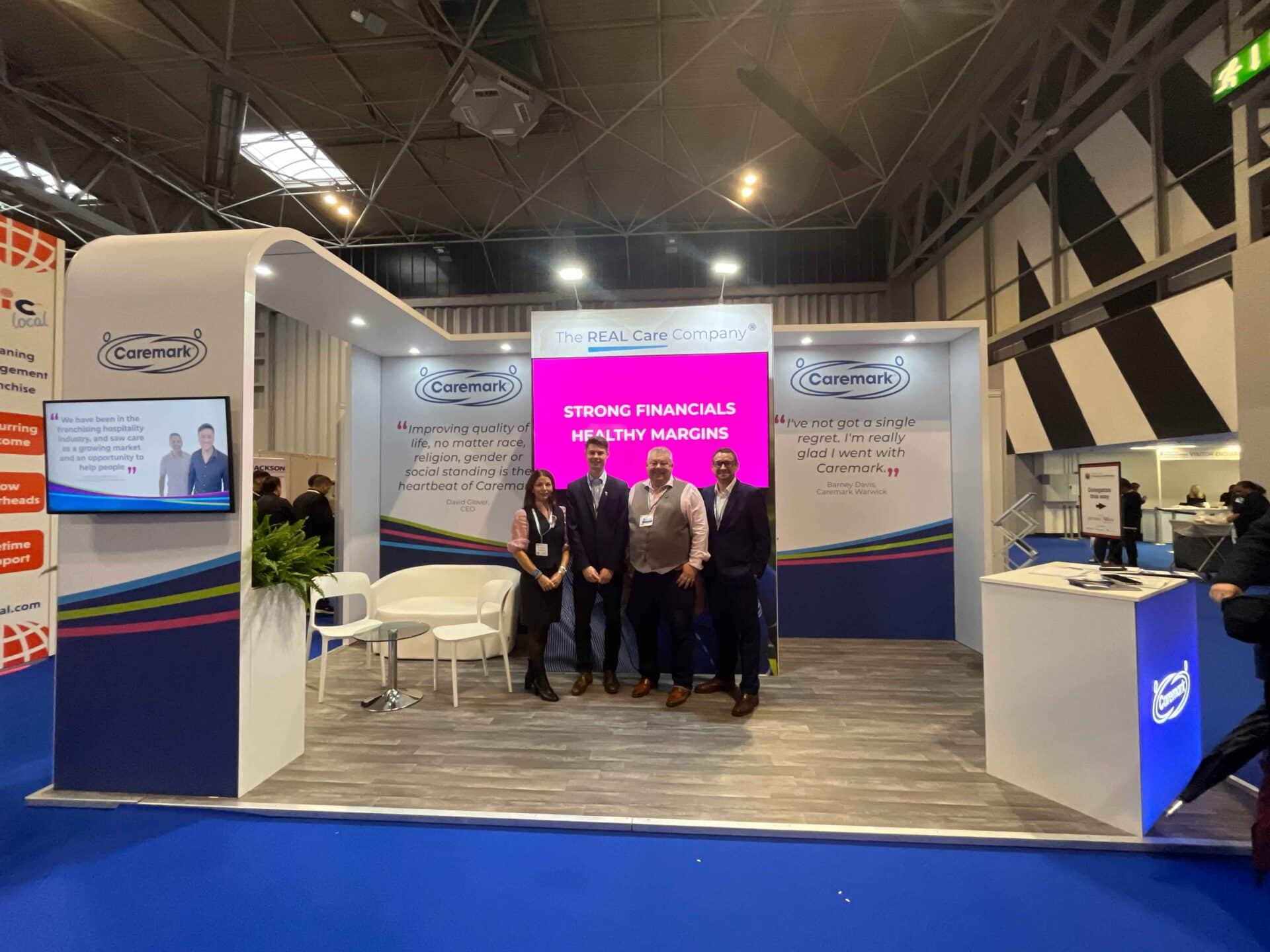 Caremark franchise team standing at the Caremark exhibition stand at the NEC, promoting home care franchise opportunities.