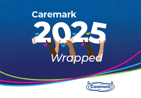 Caremark 2025 Wrapped graphic showing hands holding the number 2025 with small hearts, on a blue background with Caremark brand wave lines and logo.