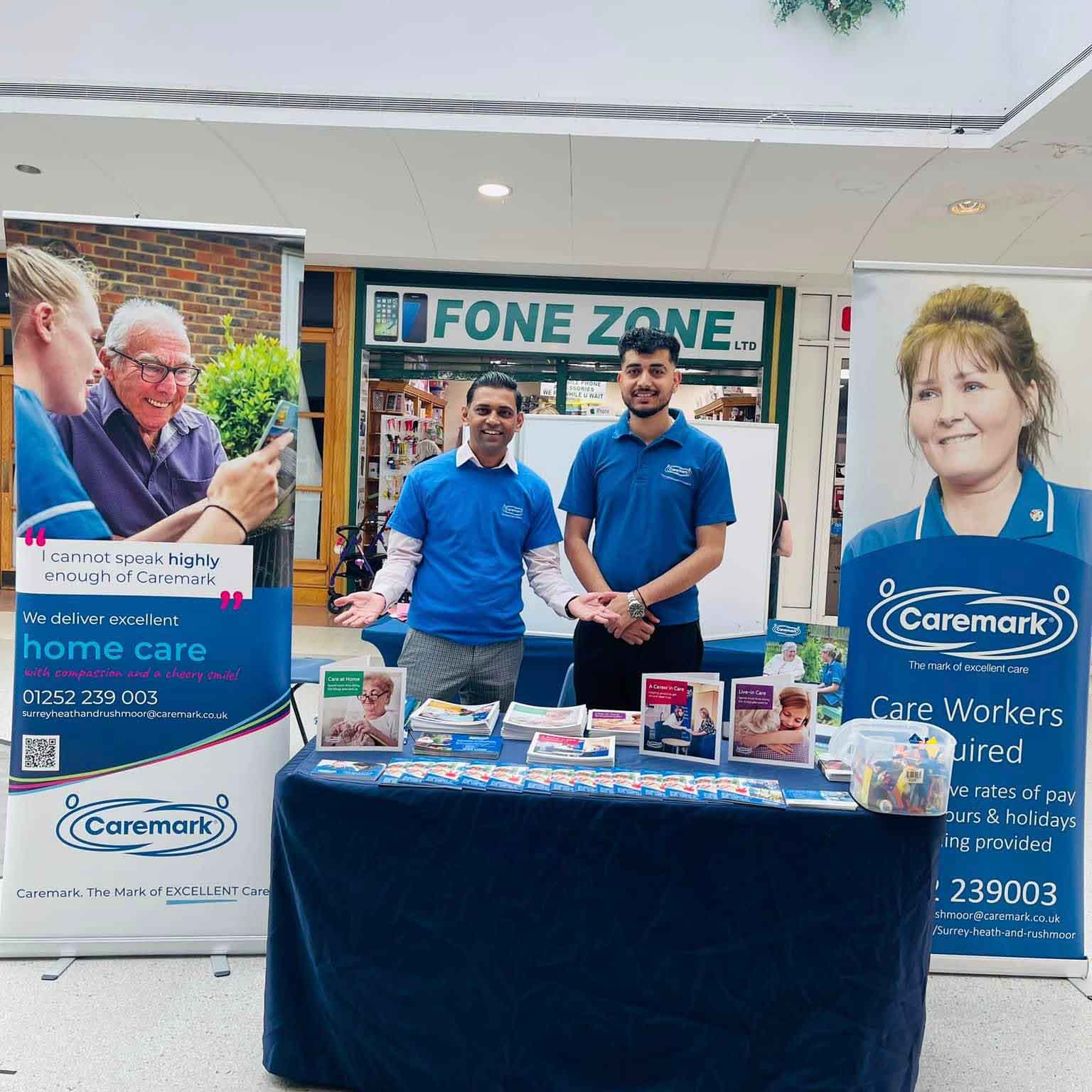 Dev and team at a Caremark Surrey Heath and Rushmoor community stall promoting home care services and care worker recruitment.