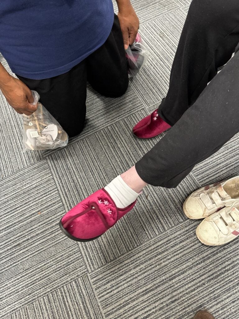 Caremark North Hertfordshire and Stevenage client receiving new velcro slippers at the Slipper Swap 2025 at Hitchin Library
