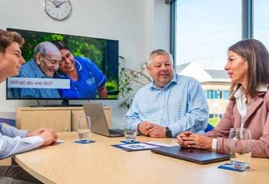 Caremark franchise recruitment meeting showing prospective franchise owners talking with the Caremark team about buying a home care franchise in a modern office setting.