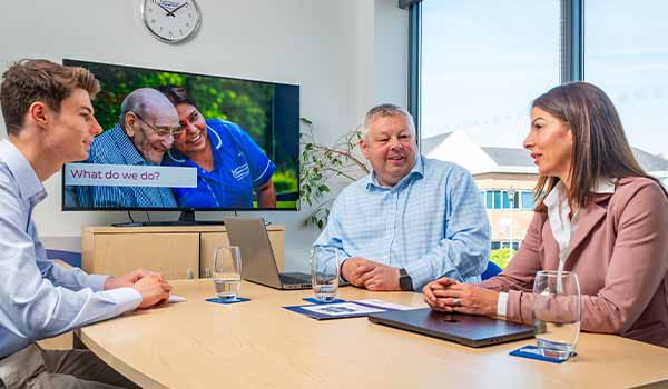 Caremark franchise recruitment meeting showing prospective franchise owners talking with the Caremark team about buying a home care franchise in a modern office setting.
