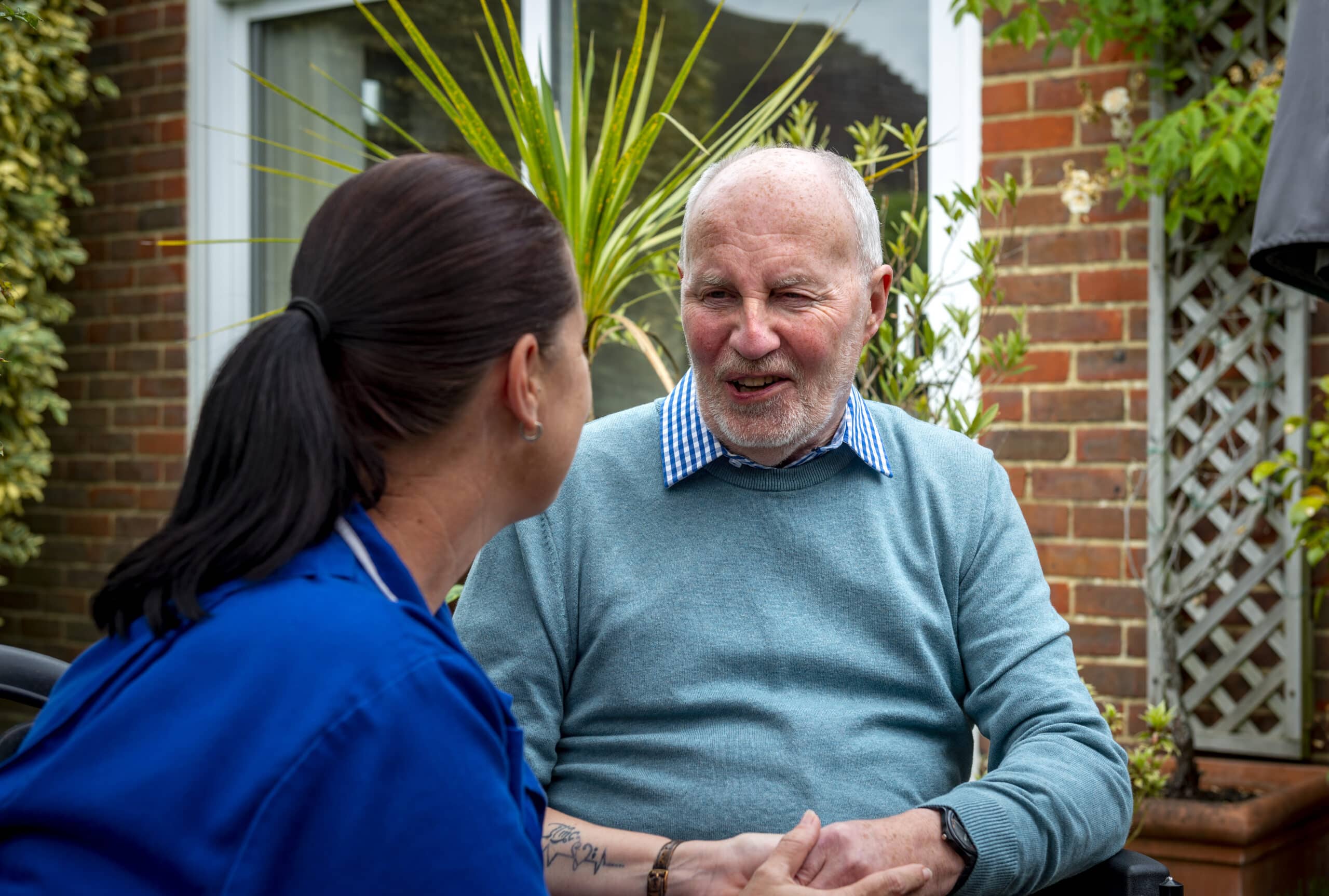 a female care assistant holding a male clients hand
