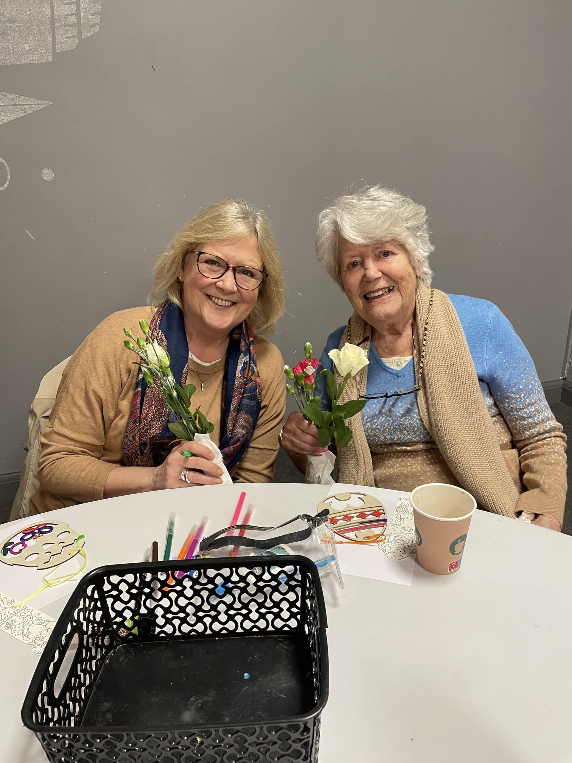Mother and daughter smiling while holding flowers
