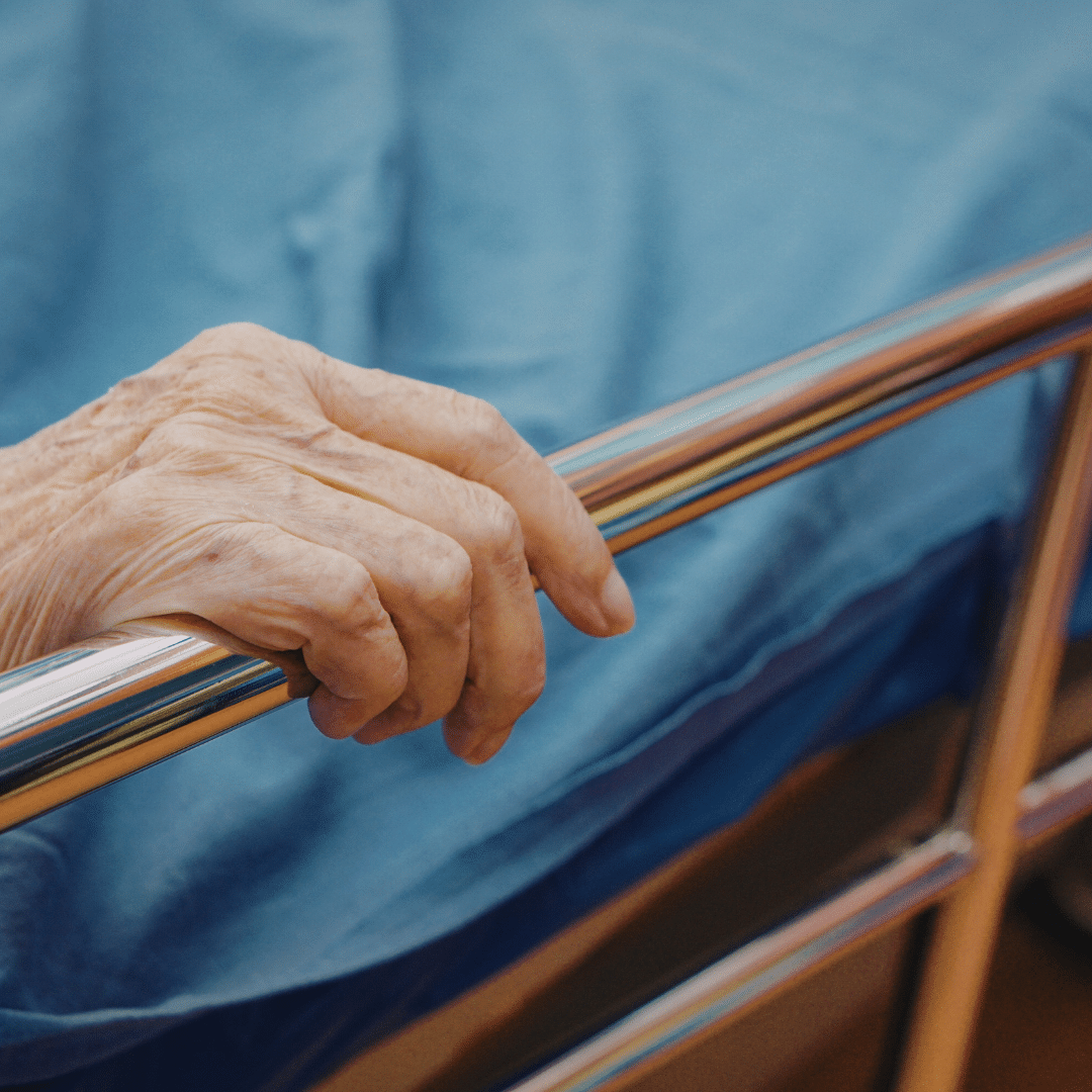 hand of an individual on a silver handrail that prevents falls at home