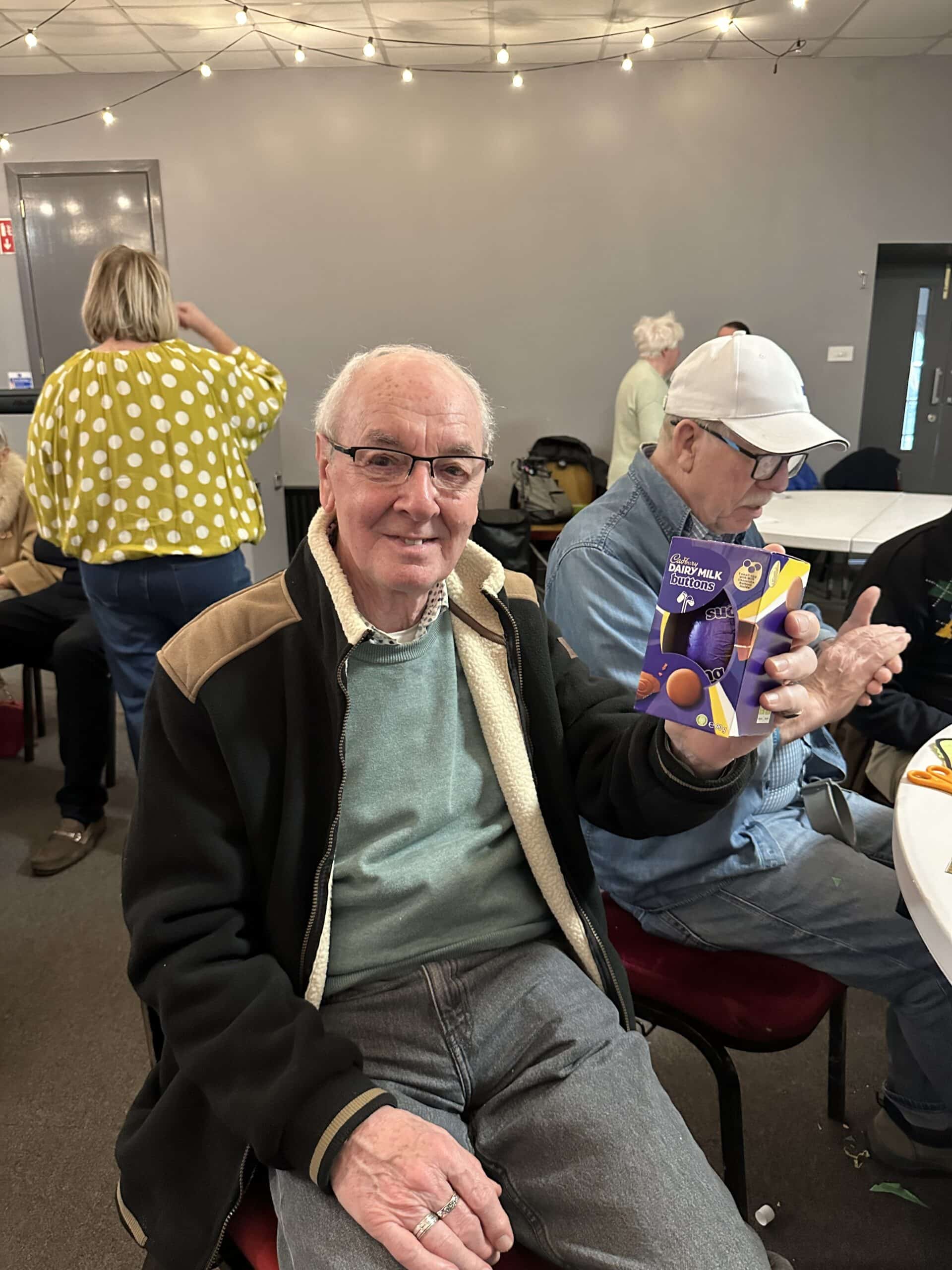 Service user smiling while holding an easter egg March Memory Cafe