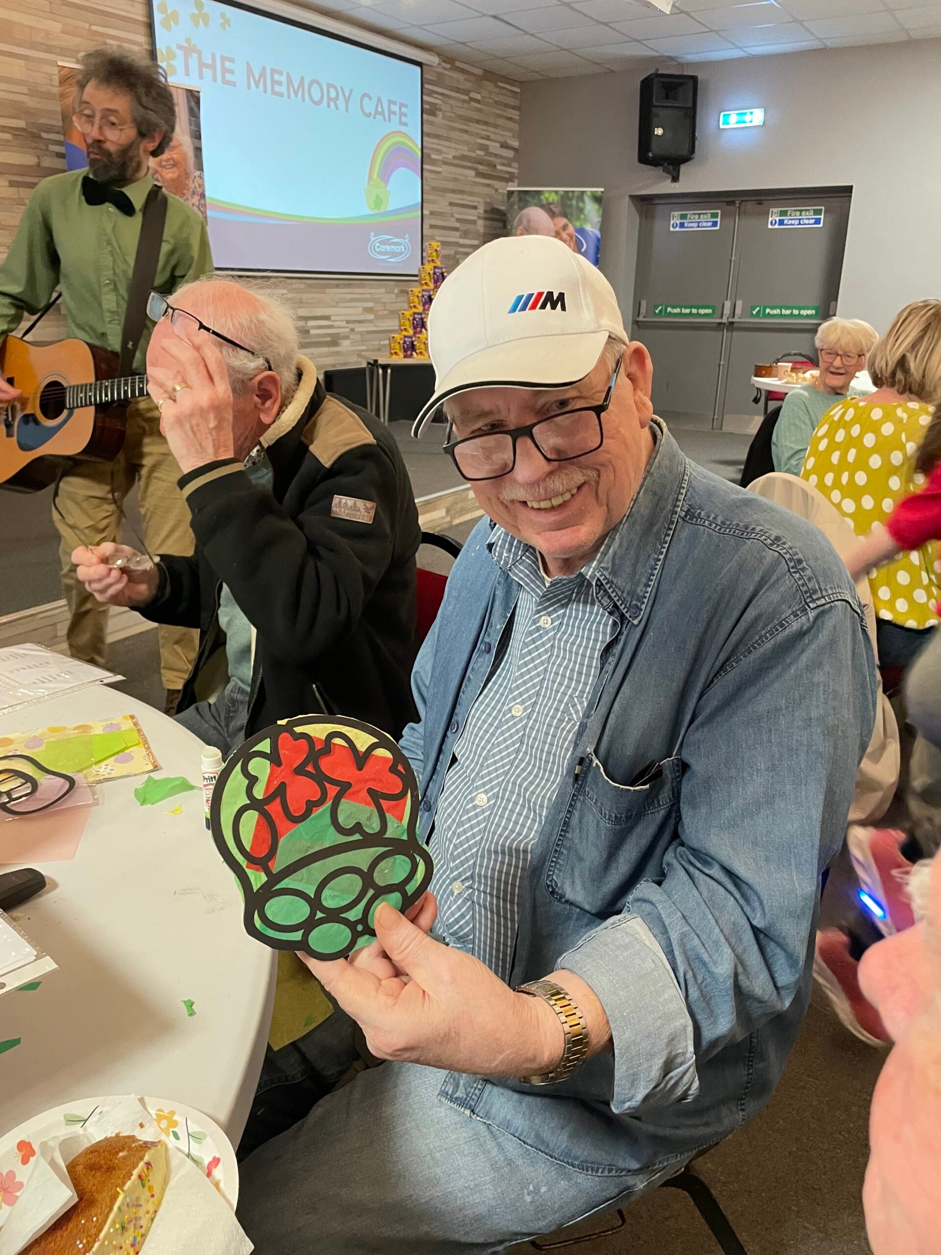 Service user smiling and showing off the St Patrick’s Day suncatcher he made during arts and crafts