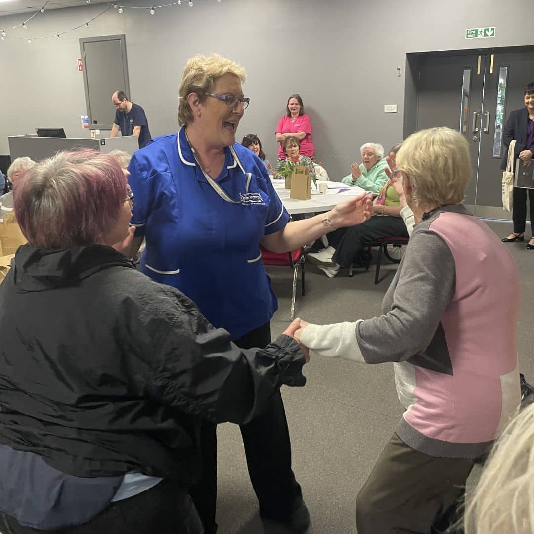 Two service users dancing with a care assistant at the Memory Cafe