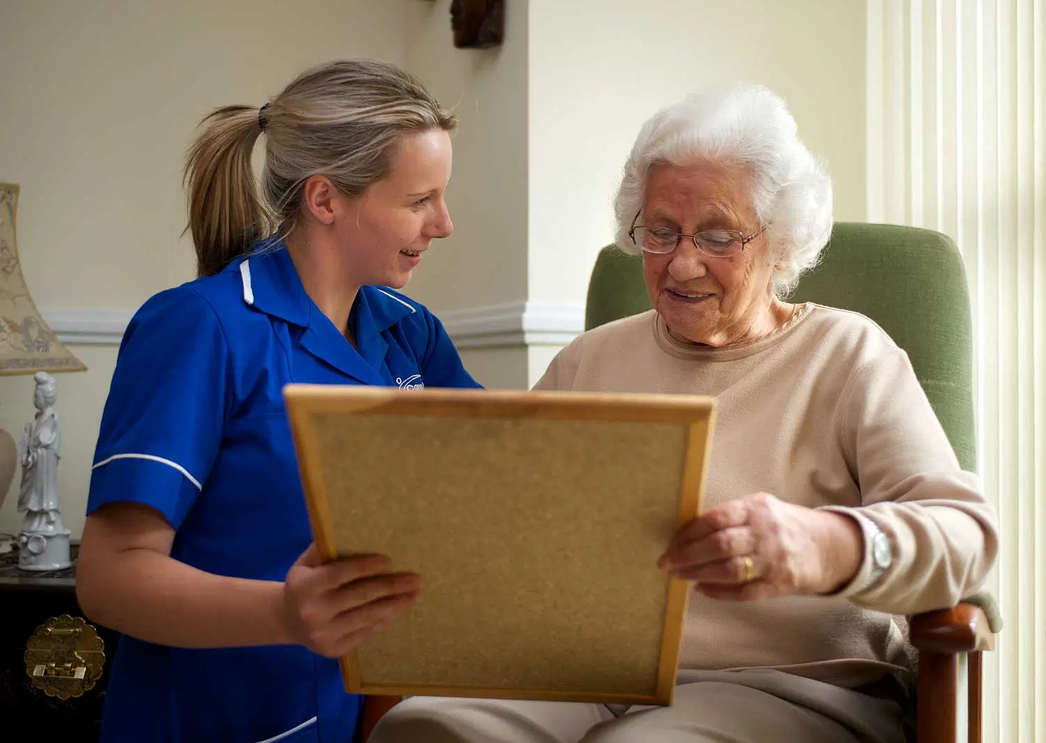 Caregiver showing photos to an elderly person to support memory and dementia care at home