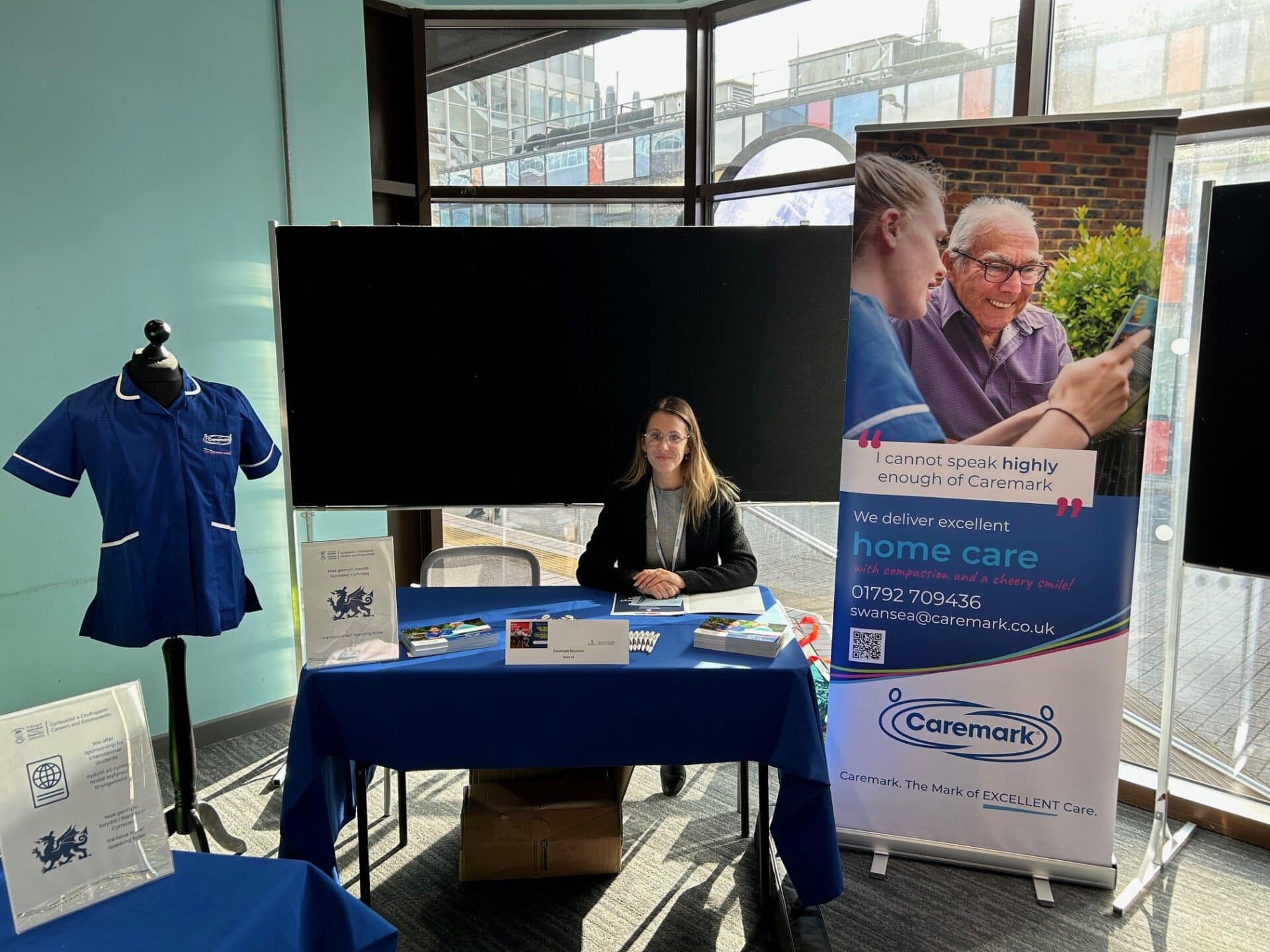 Caremark Swansea home care franchise stand at a local event, with branded materials, care uniform and team member speaking to visitors.