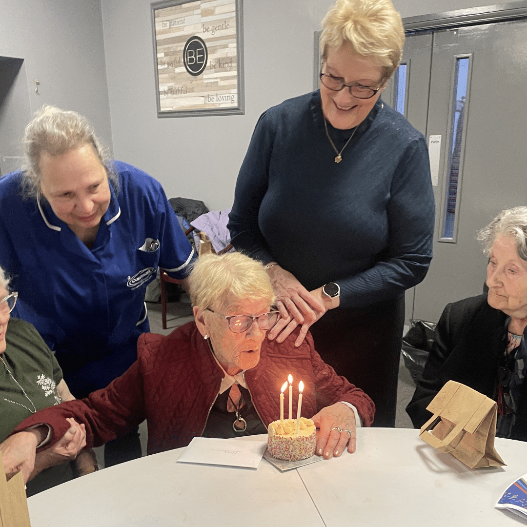 service user blowing out candles on her birthday cake