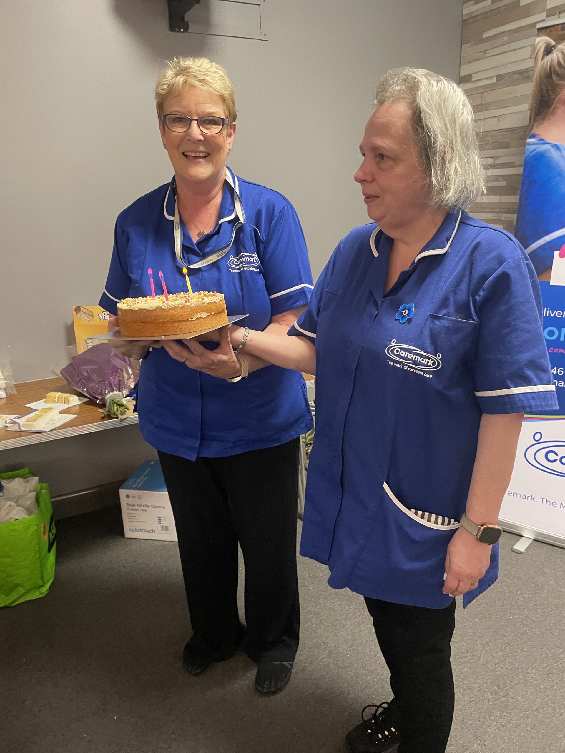 two care assistants holding up a birthday cake