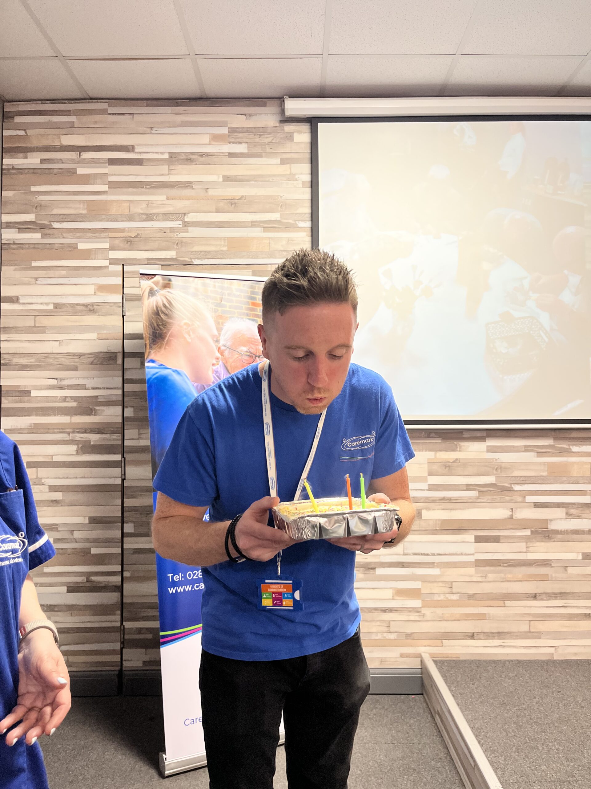 member of staff blowing out candles on a birthday cake