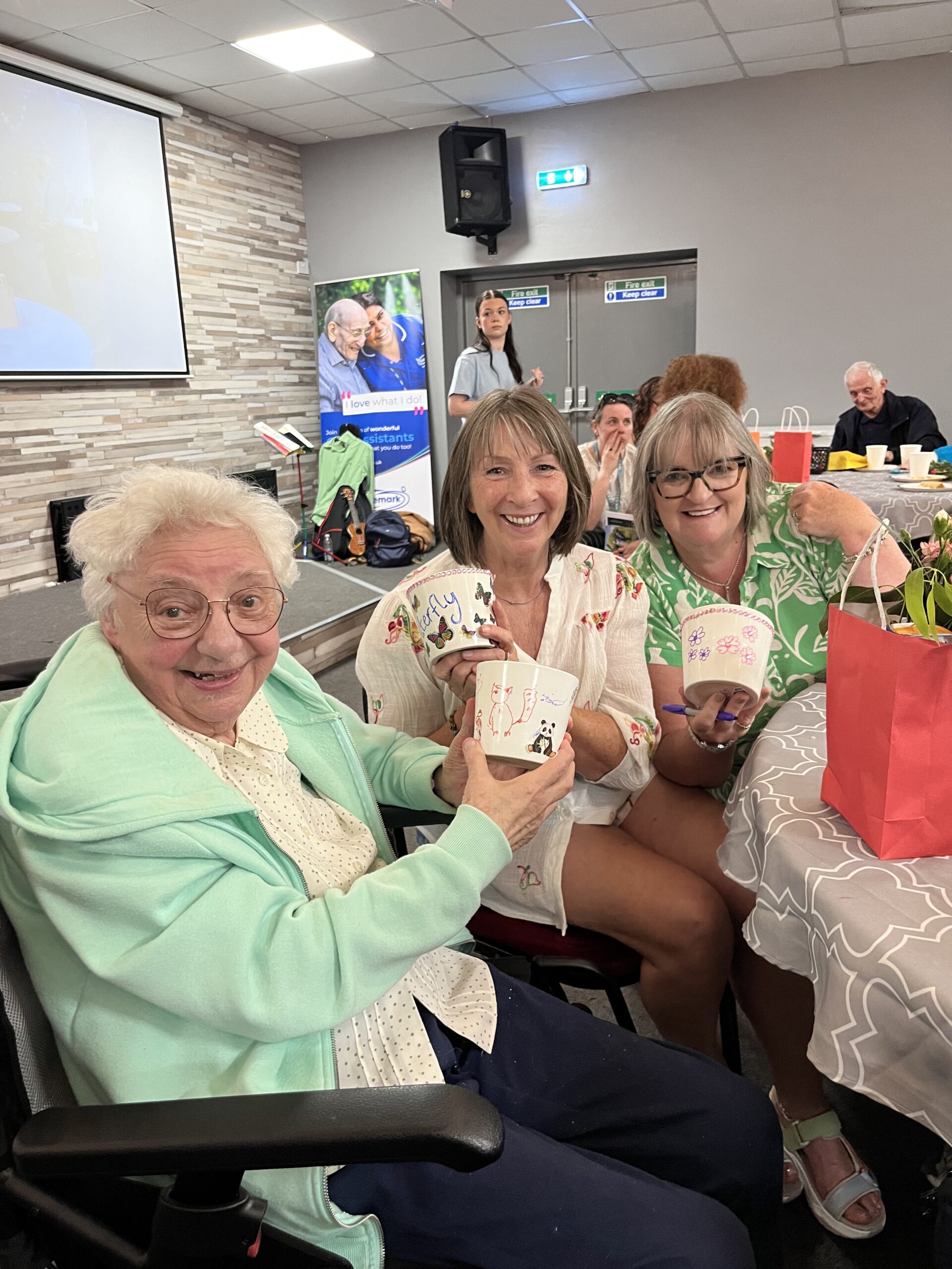 three service users holding up their decorated pots