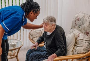 A carer helps an elderly lady